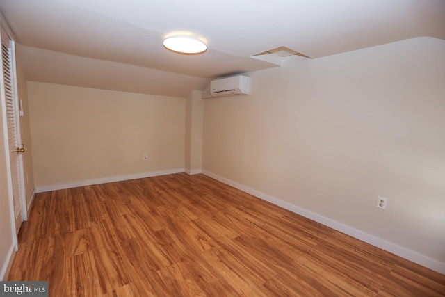 basement with a wall mounted air conditioner and light wood-type flooring