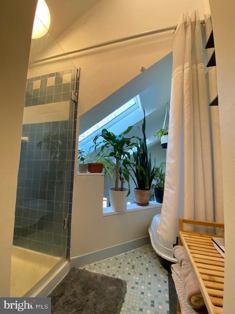 bathroom with a tile shower and vaulted ceiling