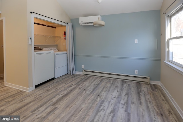 laundry area with washer and dryer, a baseboard radiator, a wall mounted air conditioner, and a healthy amount of sunlight