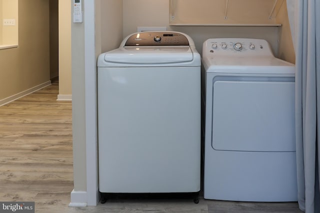 laundry room featuring washing machine and dryer and light hardwood / wood-style flooring