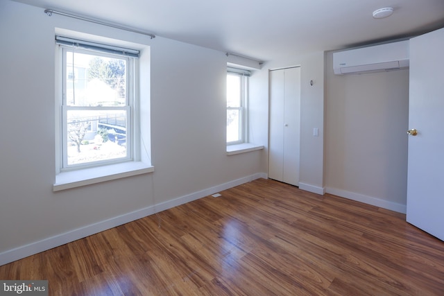 unfurnished bedroom with an AC wall unit and dark wood-type flooring