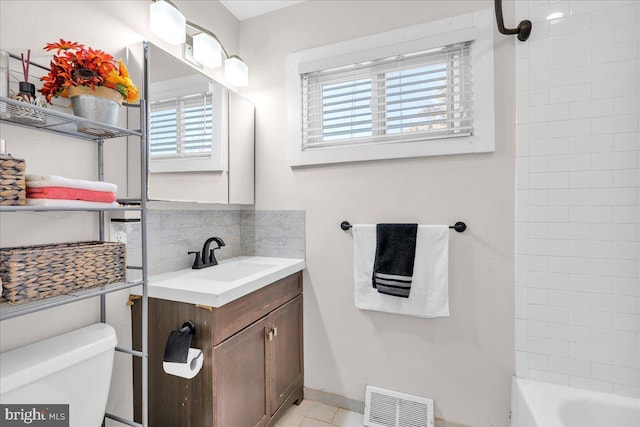 bathroom featuring toilet, vanity, and decorative backsplash