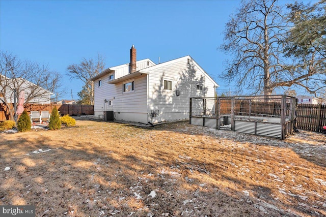 rear view of house featuring central AC unit and a lawn