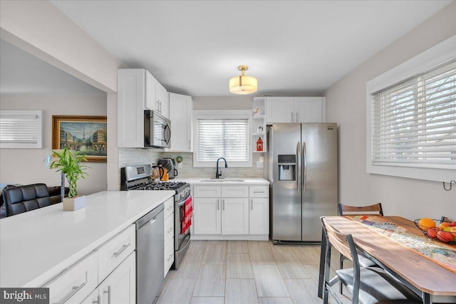 kitchen featuring white cabinets, appliances with stainless steel finishes, decorative backsplash, and sink