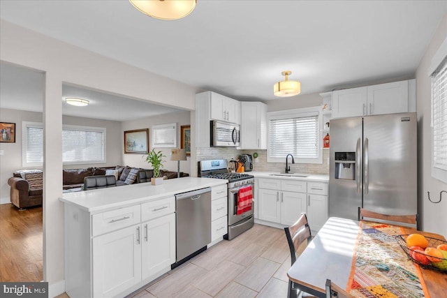 kitchen with stainless steel appliances, white cabinets, sink, and backsplash