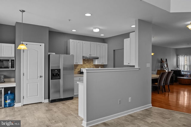 kitchen featuring pendant lighting, kitchen peninsula, light hardwood / wood-style flooring, appliances with stainless steel finishes, and white cabinetry