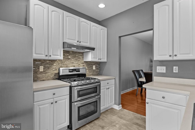 kitchen with backsplash, white cabinetry, light hardwood / wood-style flooring, and range with two ovens