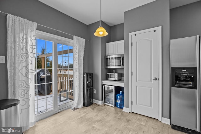 kitchen with stainless steel appliances, light hardwood / wood-style flooring, white cabinets, wine cooler, and hanging light fixtures