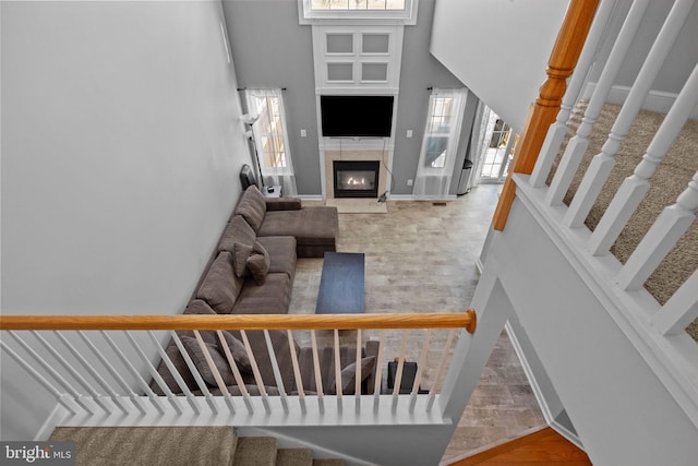 stairway featuring a fireplace, hardwood / wood-style floors, and a towering ceiling