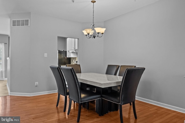 dining room with light hardwood / wood-style flooring and a notable chandelier