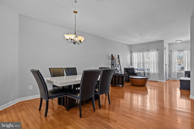 dining area with light wood-type flooring and an inviting chandelier