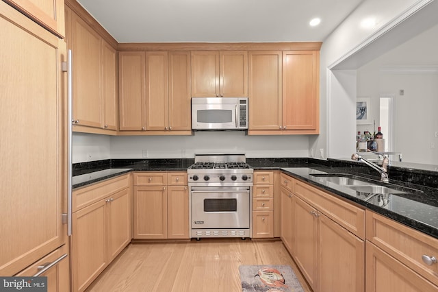 kitchen with sink, light hardwood / wood-style flooring, dark stone counters, light brown cabinetry, and appliances with stainless steel finishes