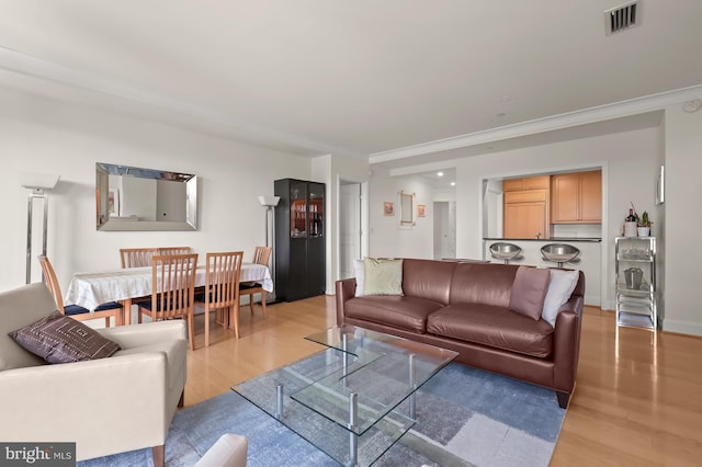 living room with light wood-type flooring and ornamental molding