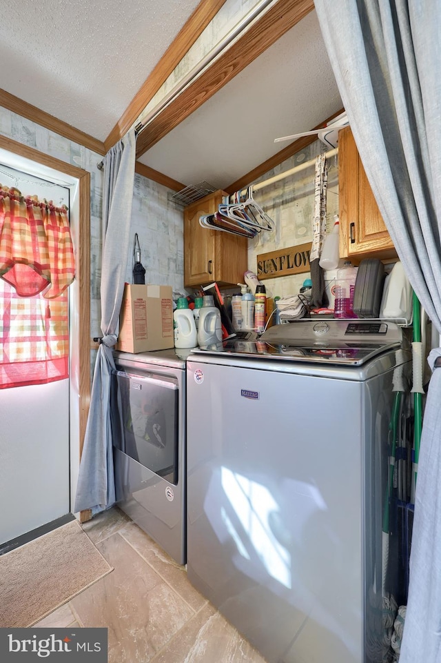 washroom featuring washer and clothes dryer, cabinets, and a textured ceiling