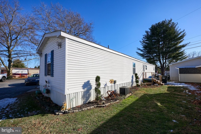 view of side of home with central AC and a yard