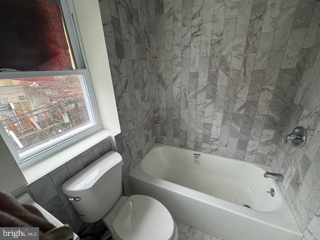 bathroom with tiled shower / bath combo and toilet