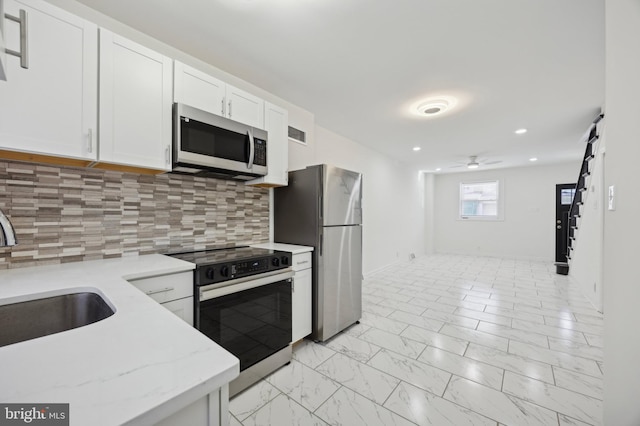 kitchen with tasteful backsplash, stainless steel appliances, ceiling fan, sink, and white cabinets