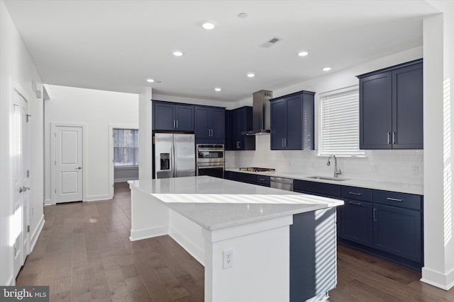 kitchen with sink, stainless steel appliances, wall chimney range hood, dark hardwood / wood-style floors, and a kitchen island