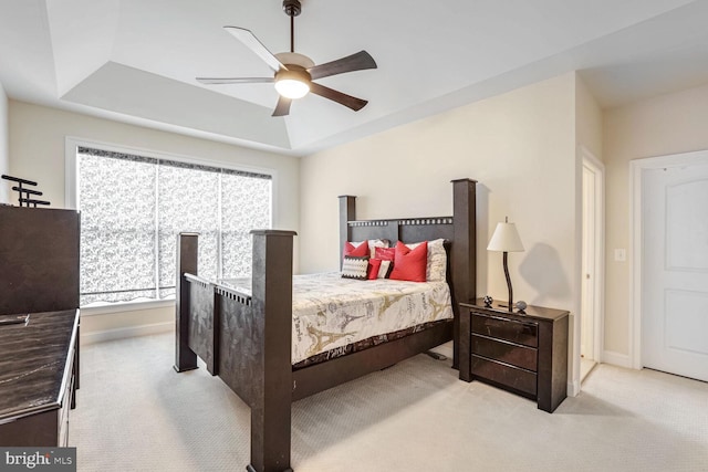 carpeted bedroom featuring ceiling fan and a raised ceiling