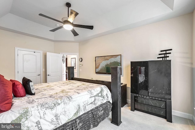 carpeted bedroom with ceiling fan and a tray ceiling