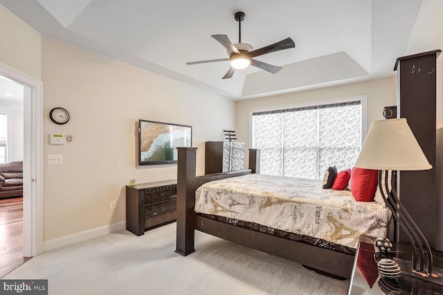 carpeted bedroom featuring ceiling fan and a tray ceiling