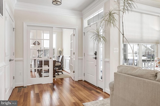 foyer entrance with hardwood / wood-style floors and crown molding