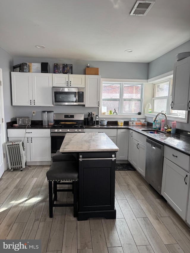 kitchen featuring sink, a kitchen island, a healthy amount of sunlight, white cabinetry, and stainless steel appliances