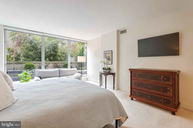 bedroom with light colored carpet and a wall of windows