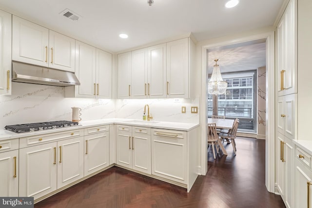 kitchen featuring dark parquet flooring, white cabinetry, sink, backsplash, and stainless steel gas stovetop