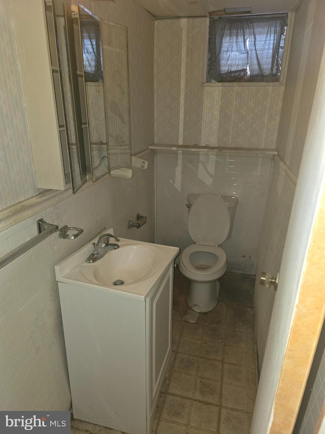 bathroom with vanity, tile walls, and toilet