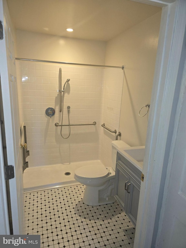 bathroom with toilet, a tile shower, vanity, and tile patterned floors