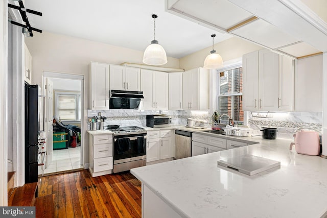 kitchen featuring white cabinetry, stainless steel appliances, decorative light fixtures, and dark hardwood / wood-style flooring