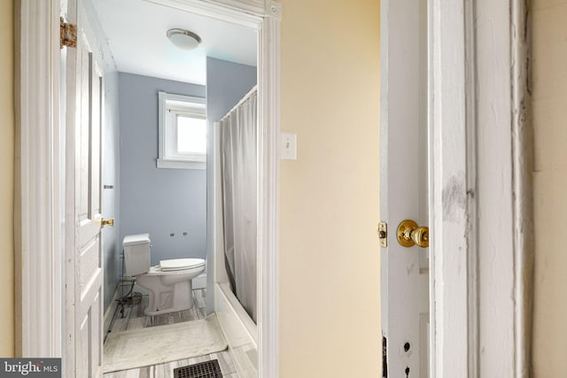 bathroom with shower / bathtub combination with curtain and toilet