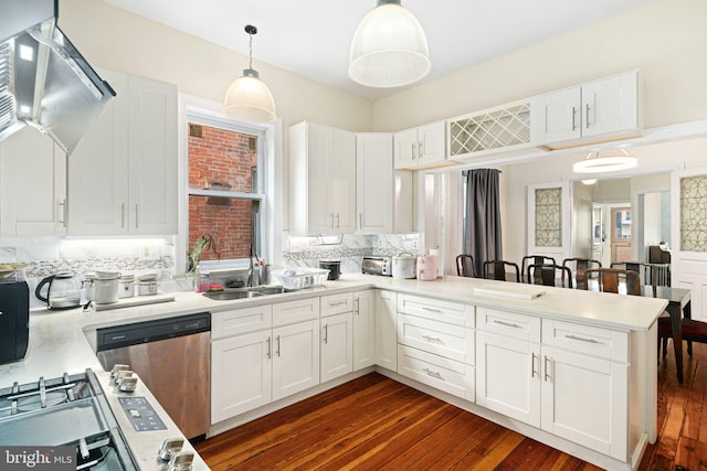 kitchen with sink, white cabinetry, hanging light fixtures, backsplash, and kitchen peninsula