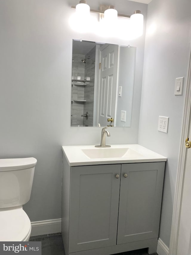 bathroom featuring vanity, toilet, and a tile shower