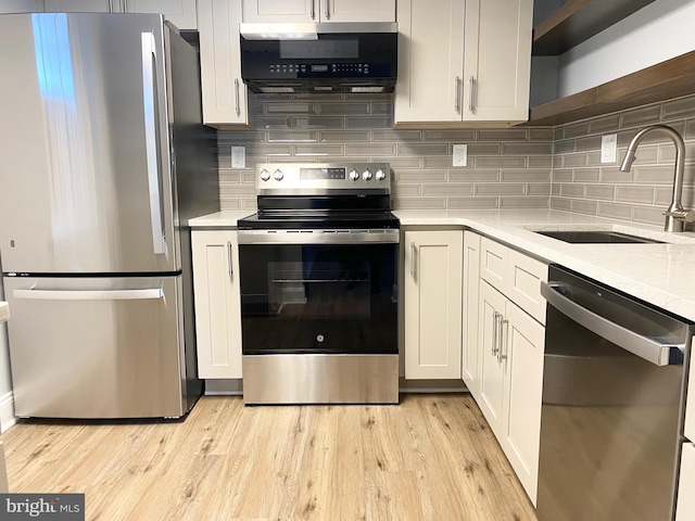 kitchen with backsplash, light stone countertops, sink, and stainless steel appliances