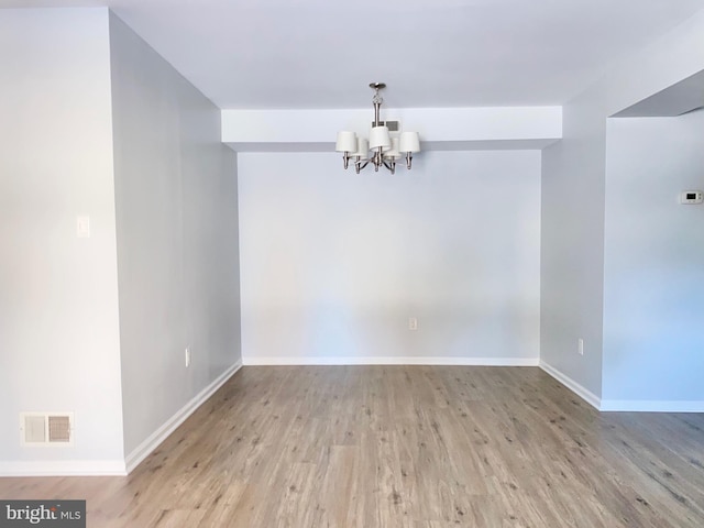 empty room featuring light hardwood / wood-style flooring and an inviting chandelier