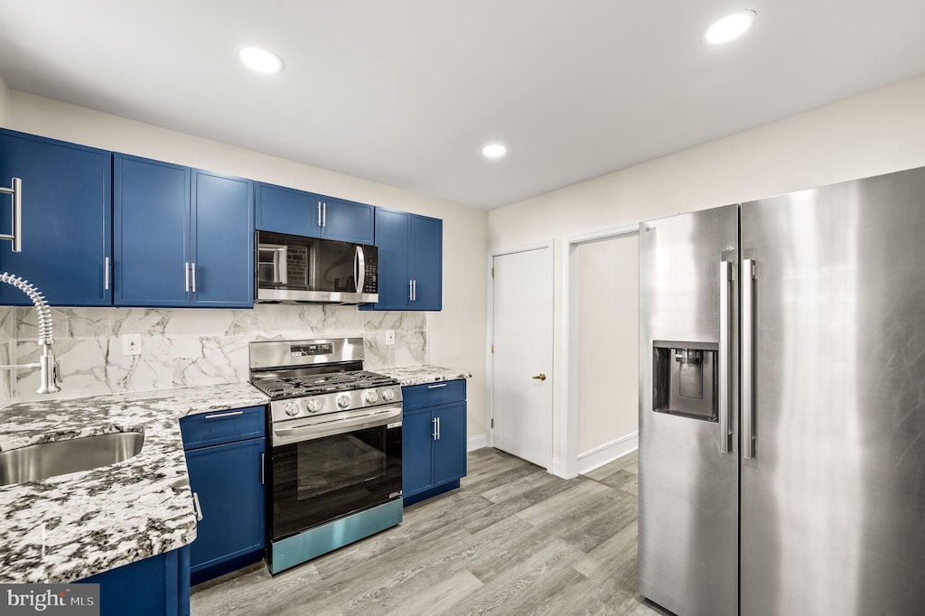 kitchen featuring blue cabinetry, decorative backsplash, sink, and stainless steel appliances