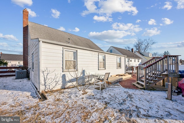 snow covered property with central air condition unit and a wooden deck