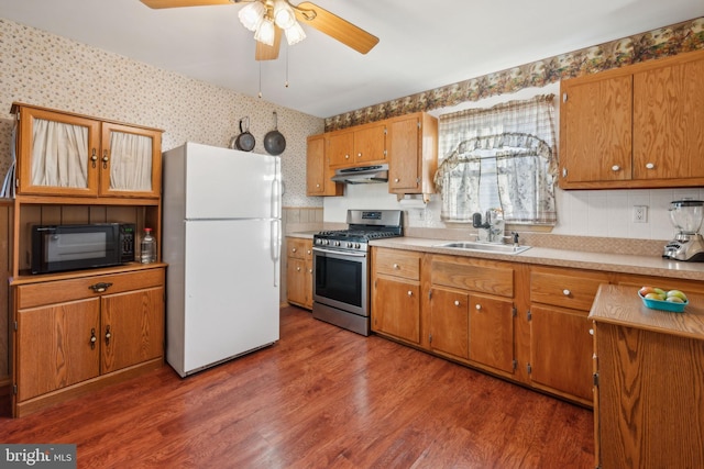 kitchen featuring white refrigerator, sink, dark hardwood / wood-style floors, ceiling fan, and stainless steel range with gas stovetop