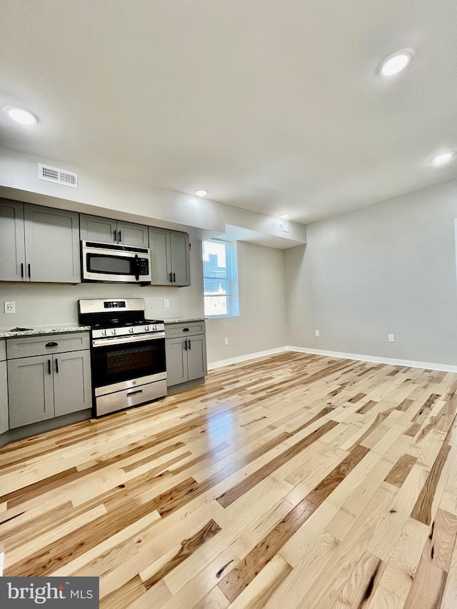 kitchen featuring stainless steel appliances, light hardwood / wood-style floors, and gray cabinetry