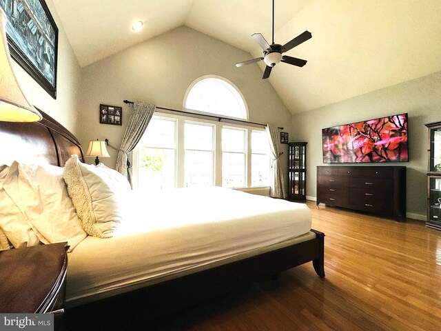 bedroom featuring hardwood / wood-style floors, high vaulted ceiling, and ceiling fan