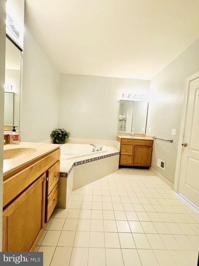 bathroom with tile patterned flooring, vanity, and tiled bath