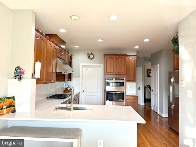 kitchen with backsplash, kitchen peninsula, sink, and appliances with stainless steel finishes