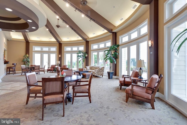 carpeted dining area featuring a wealth of natural light, french doors, and a high ceiling