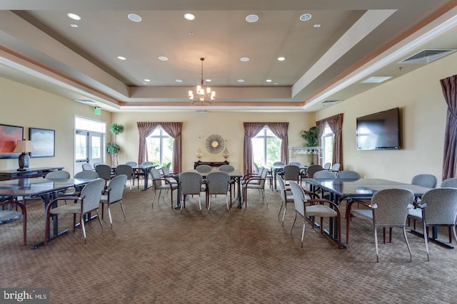 dining area featuring carpet flooring, a chandelier, a raised ceiling, and a wealth of natural light