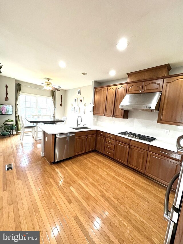 kitchen with sink, stainless steel dishwasher, light hardwood / wood-style floors, kitchen peninsula, and gas cooktop