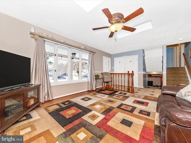 living room featuring ceiling fan and a skylight