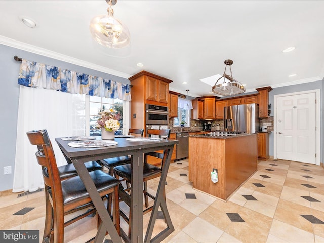 kitchen with stainless steel appliances, a kitchen island, tasteful backsplash, decorative light fixtures, and ornamental molding