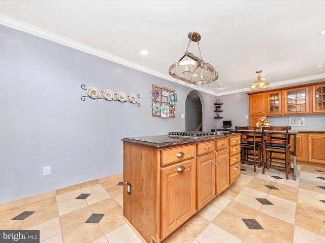 kitchen featuring decorative light fixtures, stainless steel gas stovetop, dark stone countertops, crown molding, and light tile patterned floors